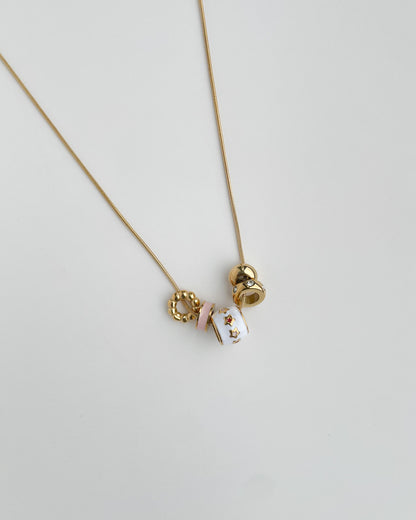 Gold necklace with three round pendants on a light gray background