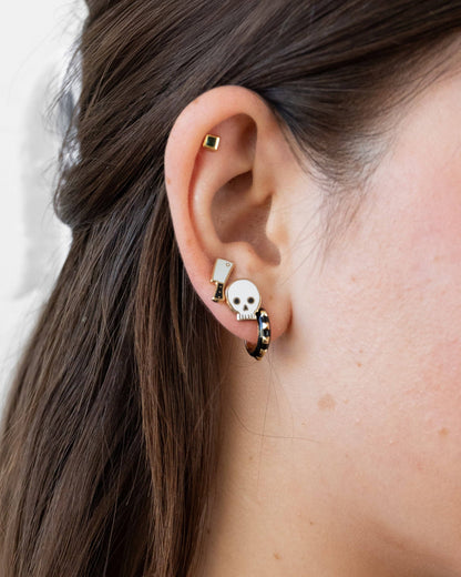 Close-up of an ear with multiple earrings against a neutral background
