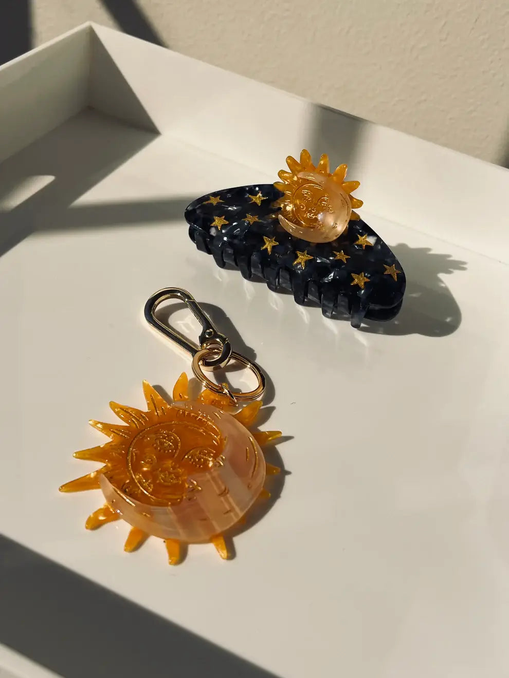 Two hair accessories with sun designs on a light surface