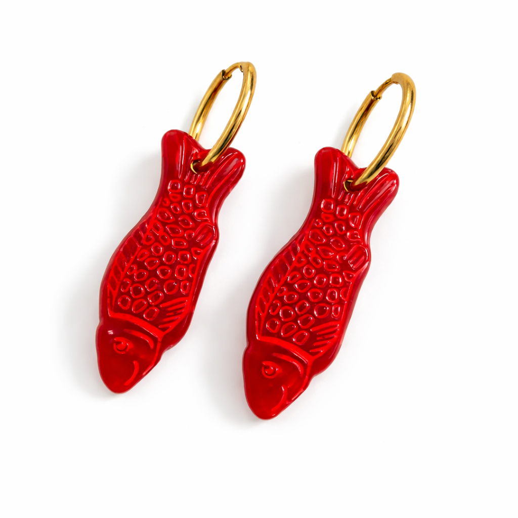 Red fish-shaped earrings with gold hooks on a white background