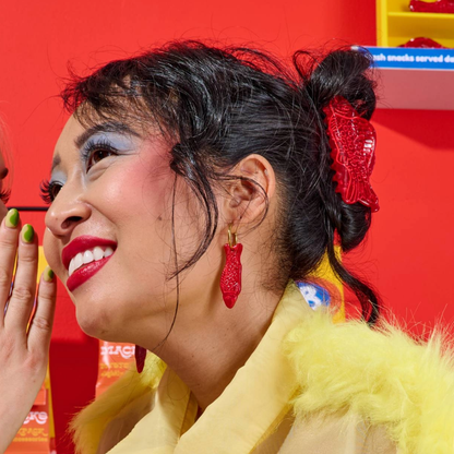 Woman with colorful makeup and red hair accessory against a red background