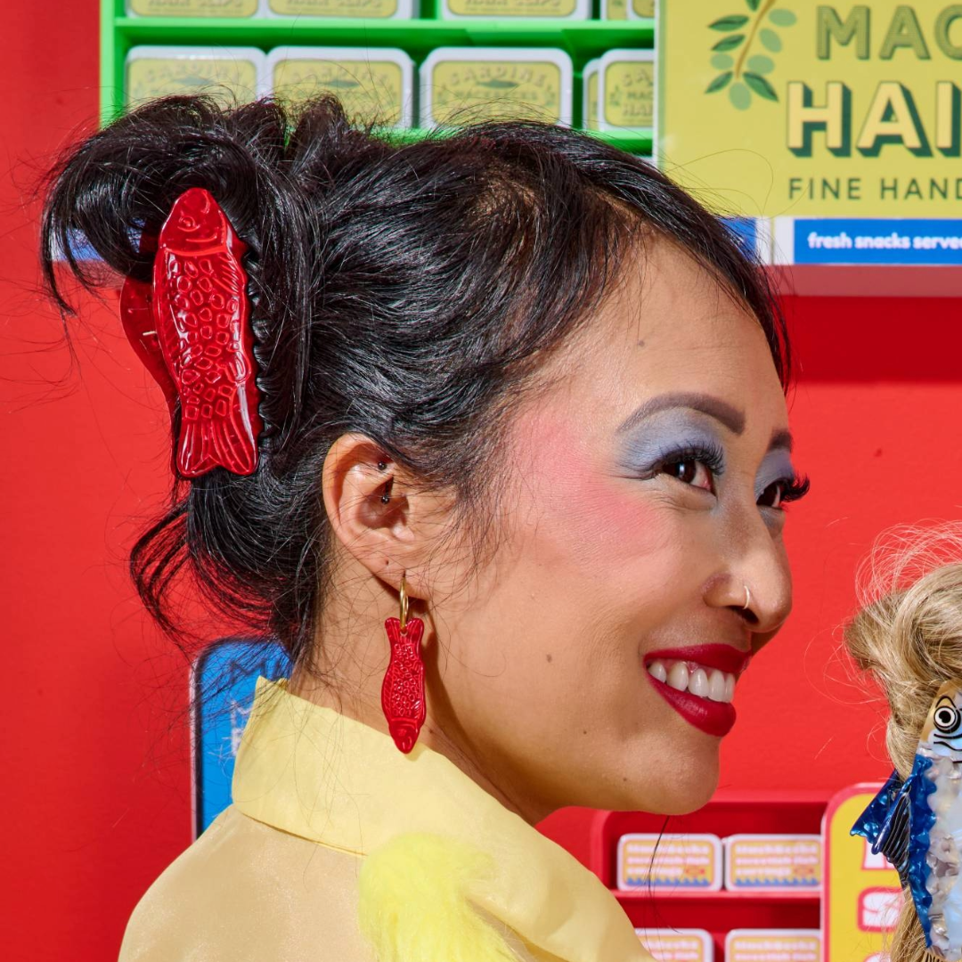 Woman with red hair clip and makeup in front of a colorful background