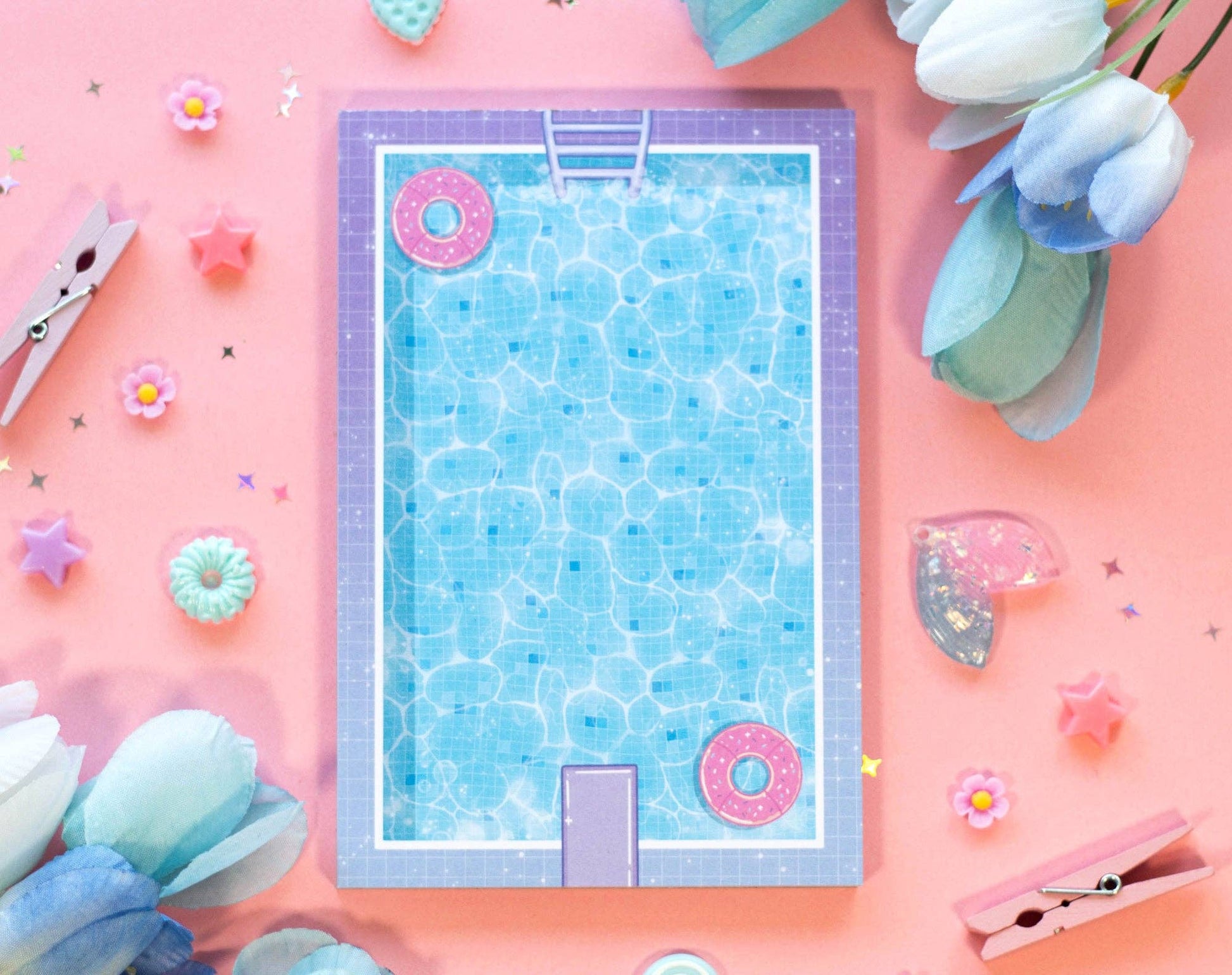 Swimming pool design on a notepad on a pink background with decorative elements.