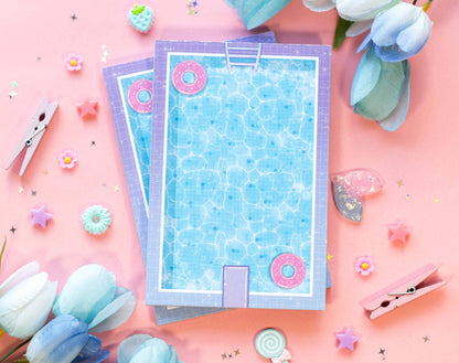 Decorative notepadwith pool design on a pink background with flowers and clips.