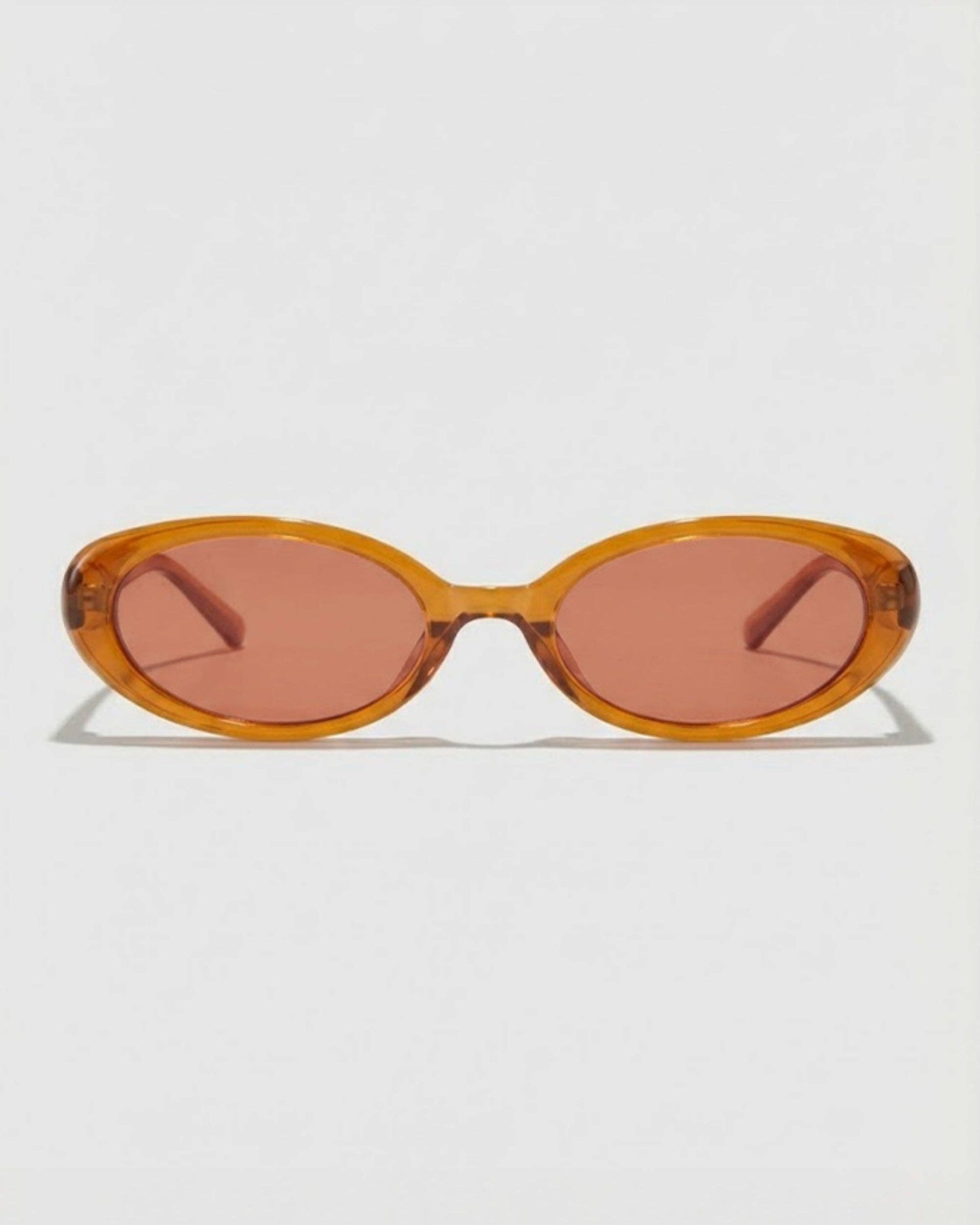 Sunglasses with a caramel colored  frame and pink lenses on a white background