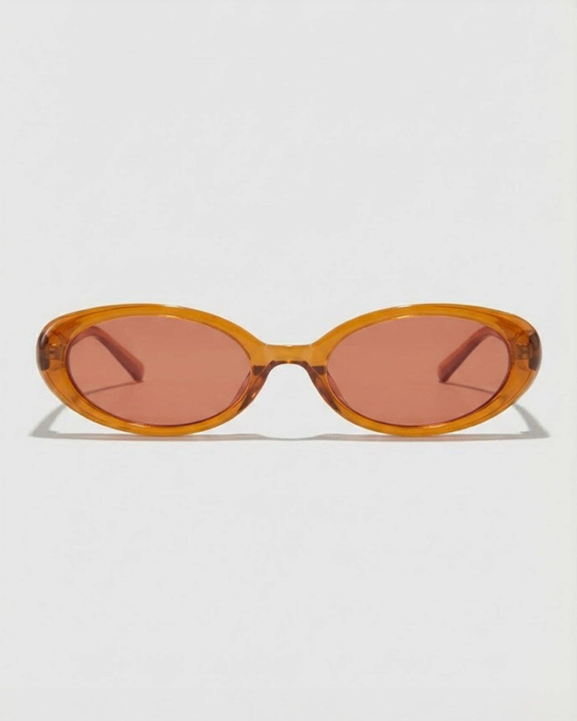 Sunglasses with a caramel colored  frame and pink lenses on a white background