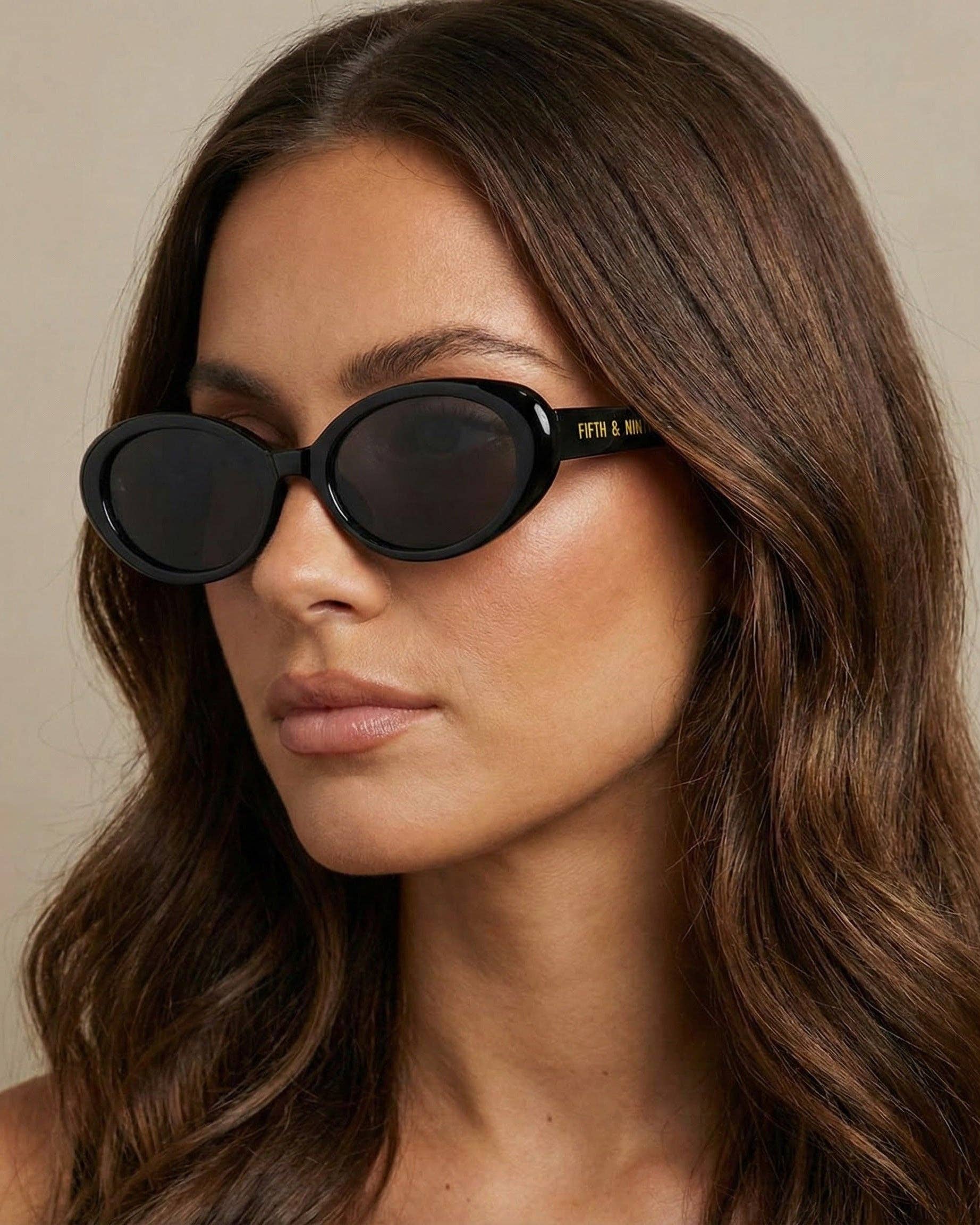 Woman wearing black sunglasses with a neutral background