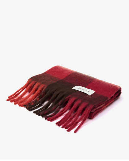 A folded red and dark brown plaid scarf with fringe tassels and a small white label, photographed on a clean white background.