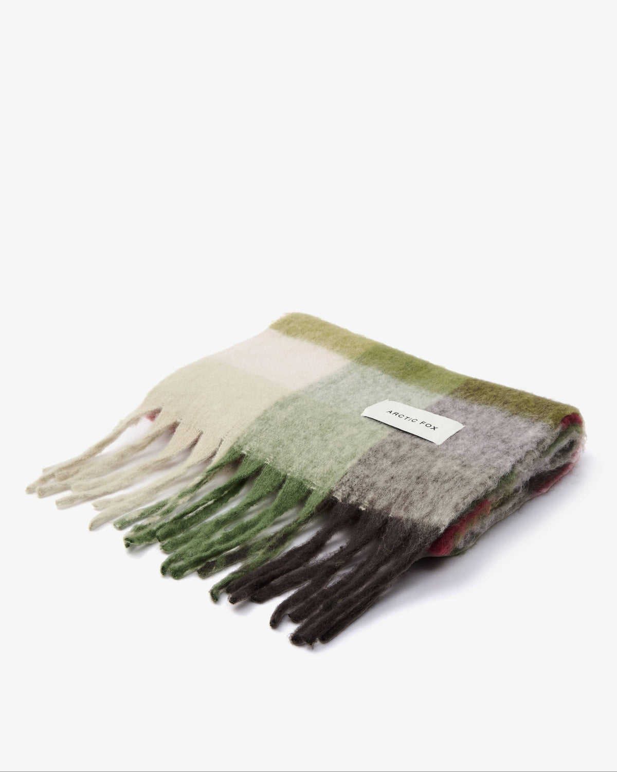 A folded fuzzy knit scarf with fringe, featuring a soft plaid pattern in sage green, cream, gray, and dark brown, with a small white brand label.