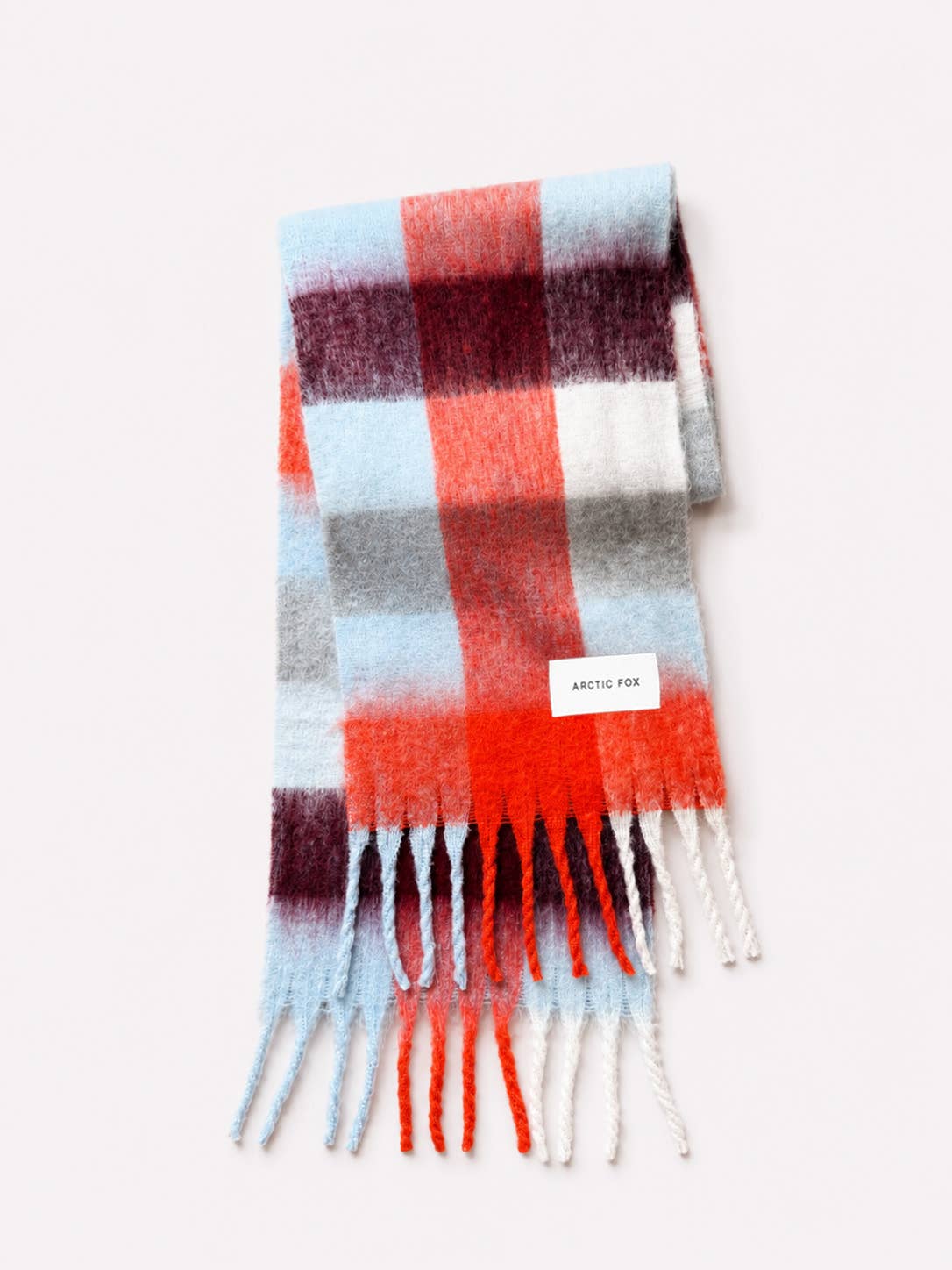 A folded plaid scarf with fringe ends, featuring stripes of light blue, coral orange, white, gray, and dark burgundy. A small white label reading 'ANTHE FOR' is visible near the top right of the scarf, set against a plain off-white background.