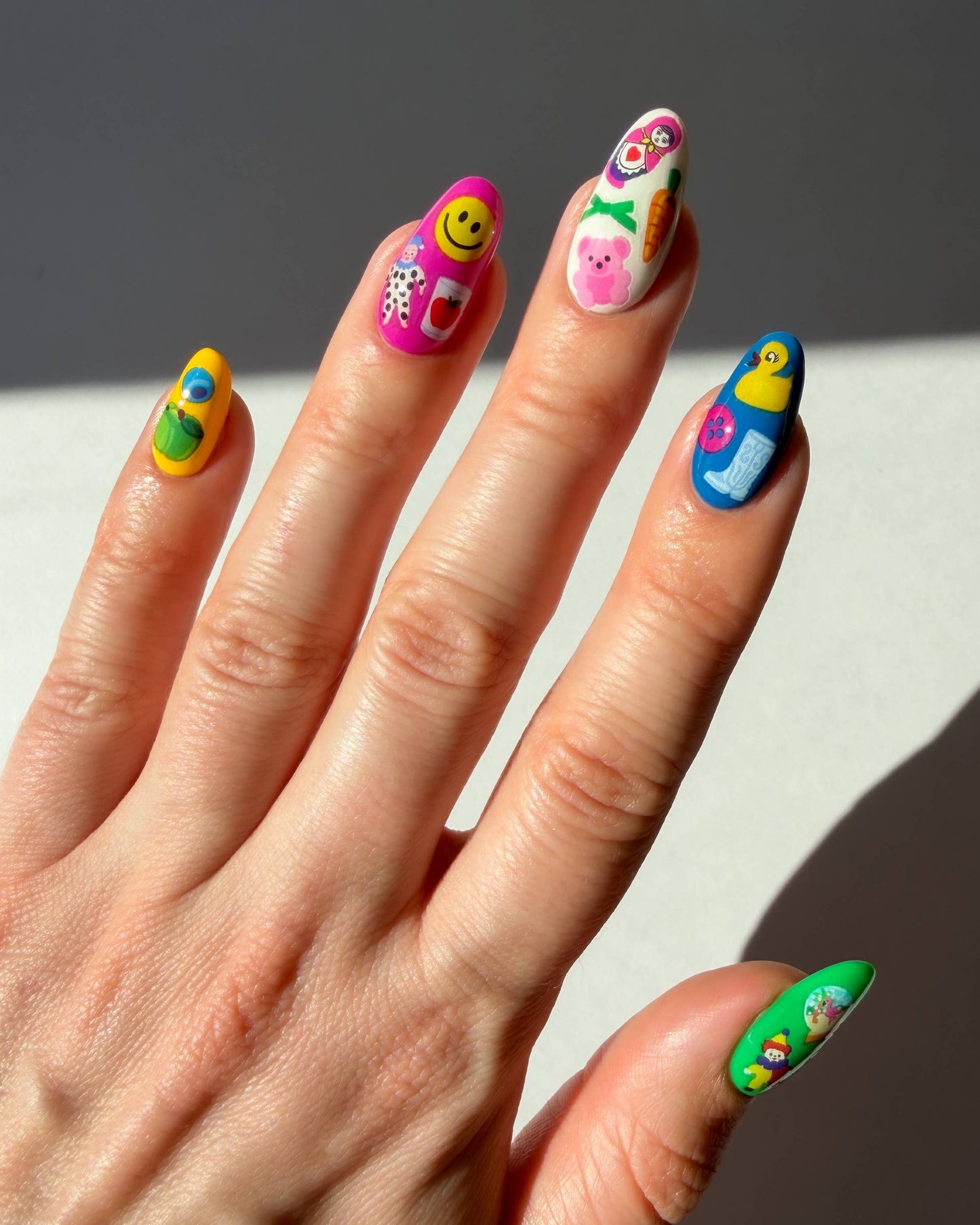 Hand with colorful nail art on a neutral background
