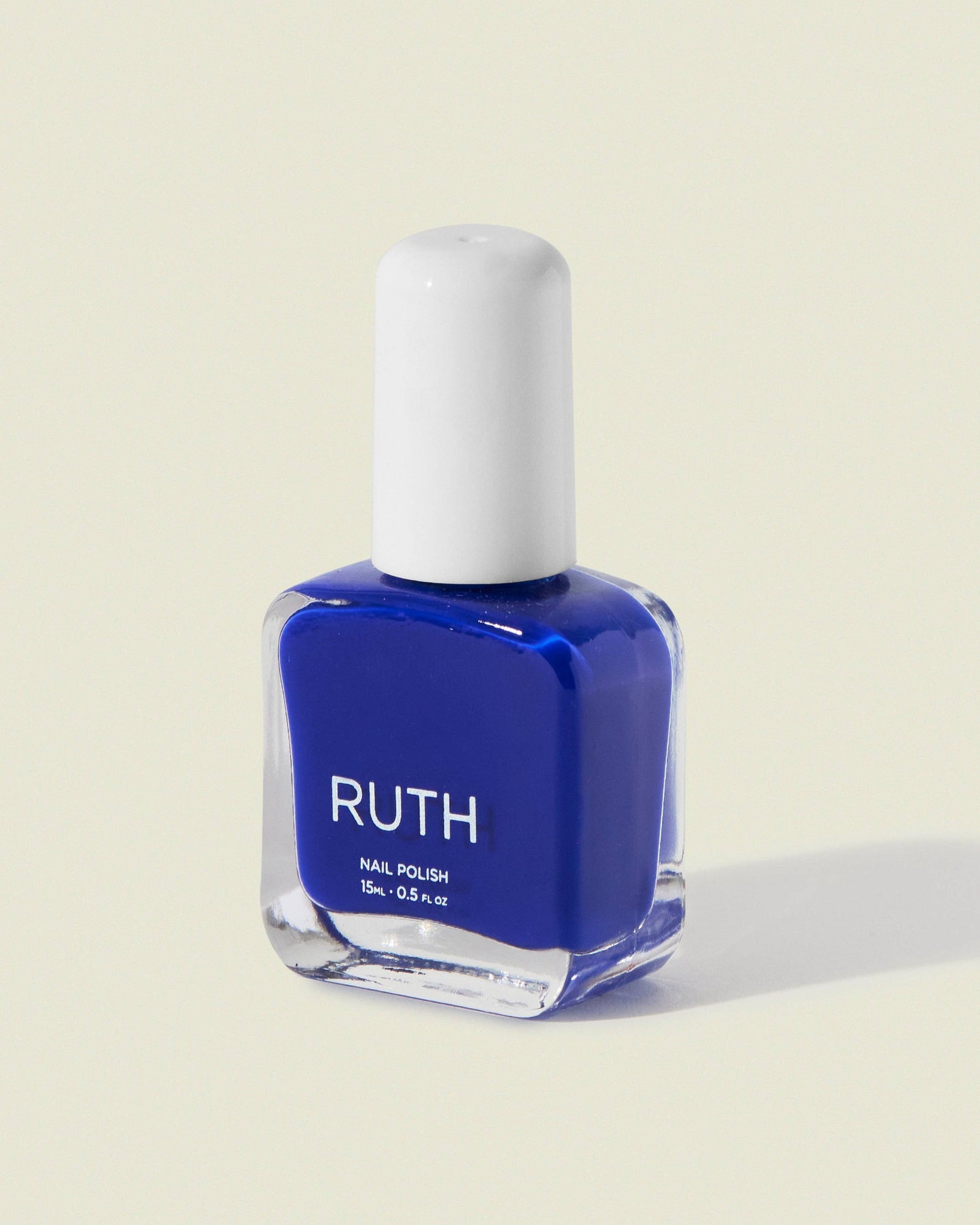 Blue nail polish bottle with white cap on a light beige background, Tide Royal Blue Nail Polish
