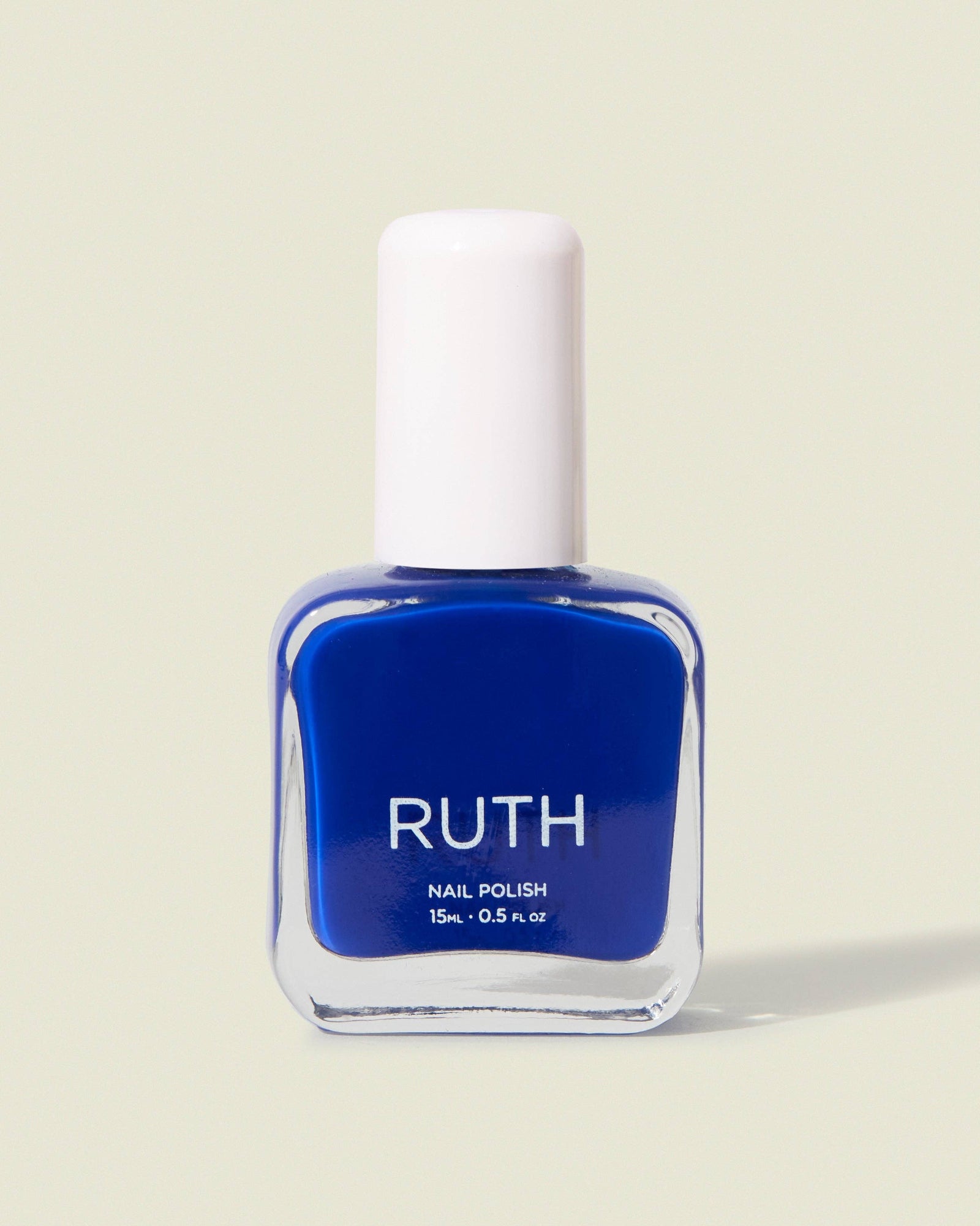 Blue nail polish bottle with white cap on a beige background, Tide Royal Blue Nail Polish