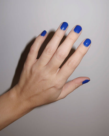 Hand with blue nail polish on a plain background, Tide Royal Blue Nail Polish