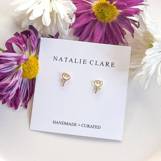 Gold earrings on a 'Natalie Clare' card with flowers around