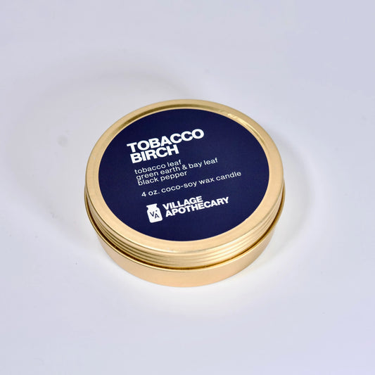 Tobacco Birch candle container with gold lid and blue label on a white background