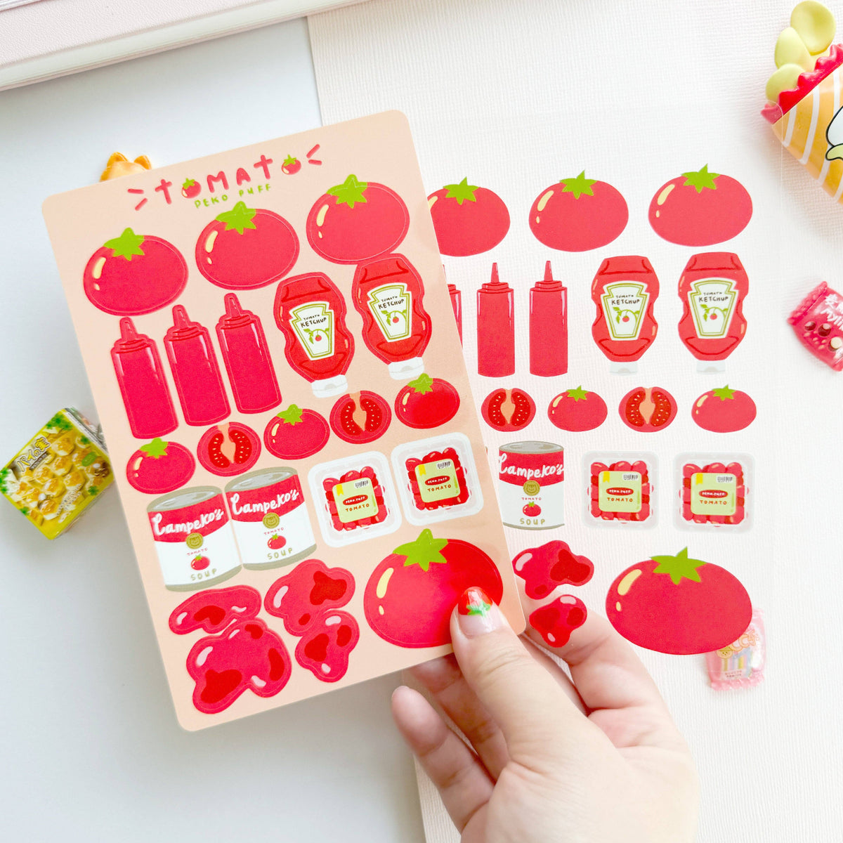 Sheet of tomato and ketchup-themed stickers held by a hand on a white surface.