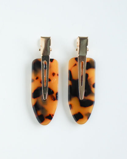 Tortoiseshell hair clips with gold hardware on a white background