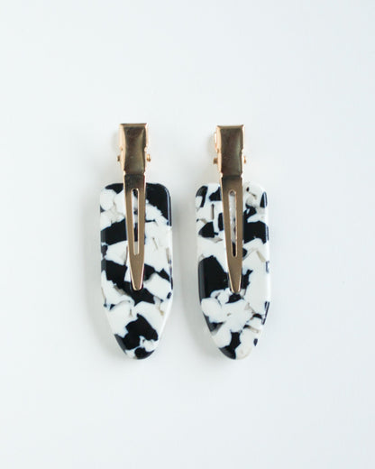 Black and white marble crease free hair clips with gold centers on a white background