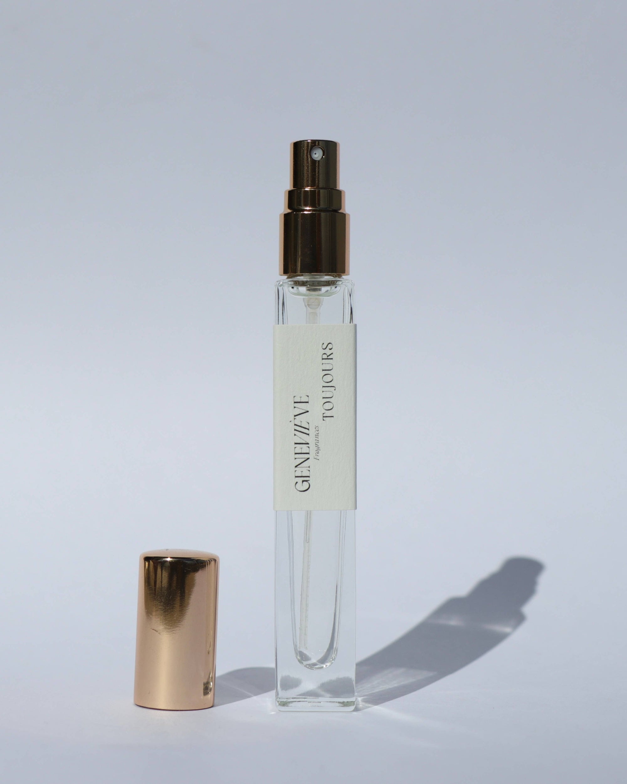 Small spray bottle with gold cap and visible brand name on a light gray background