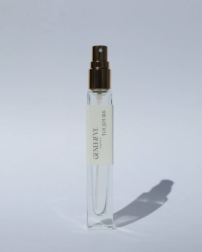 Small clear spray bottle with a gold cap on a light gray background