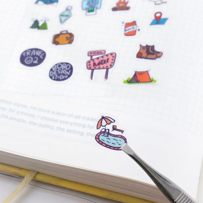 Colorful travel-themed stickers on a notebook with a pen.