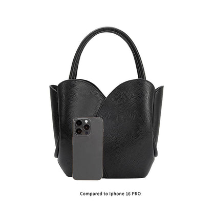 Black handbag with a smartphone inside, compared to an iPhone 16 Pro on a white background