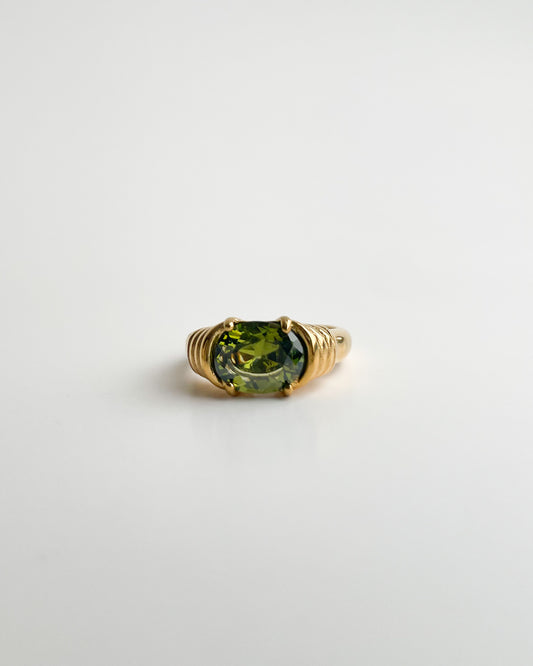 Gold ring with a green gemstone on a white background