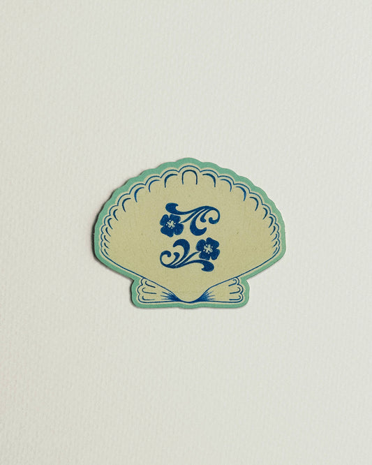 Decorative shell-shaped sticker with blue floral design on a light gray background