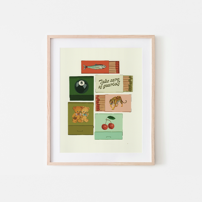 A framed art print featuring a retro-style illustration of vintage matchboxes with various designs, including a fish, an 8-ball, cherries, a tiger, and a teddy bear, displayed on a clean white background.