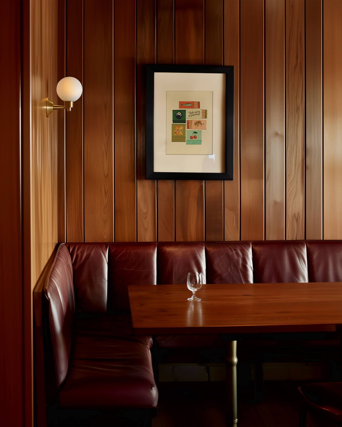 Wood-paneled room with a brown leather booth and framed picture on the wall.