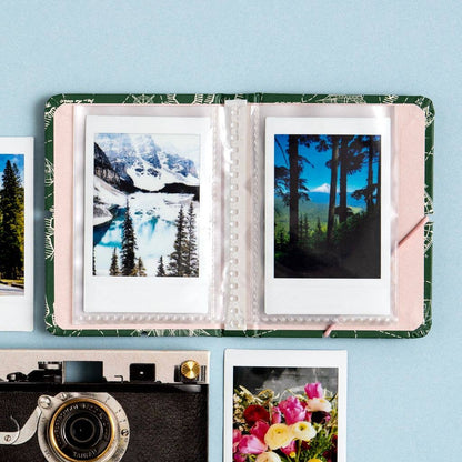 Open photo album with scenic prints on a light blue background
