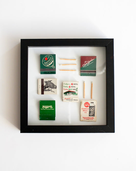 Framed display of vintage matchbooks with matches on a white background