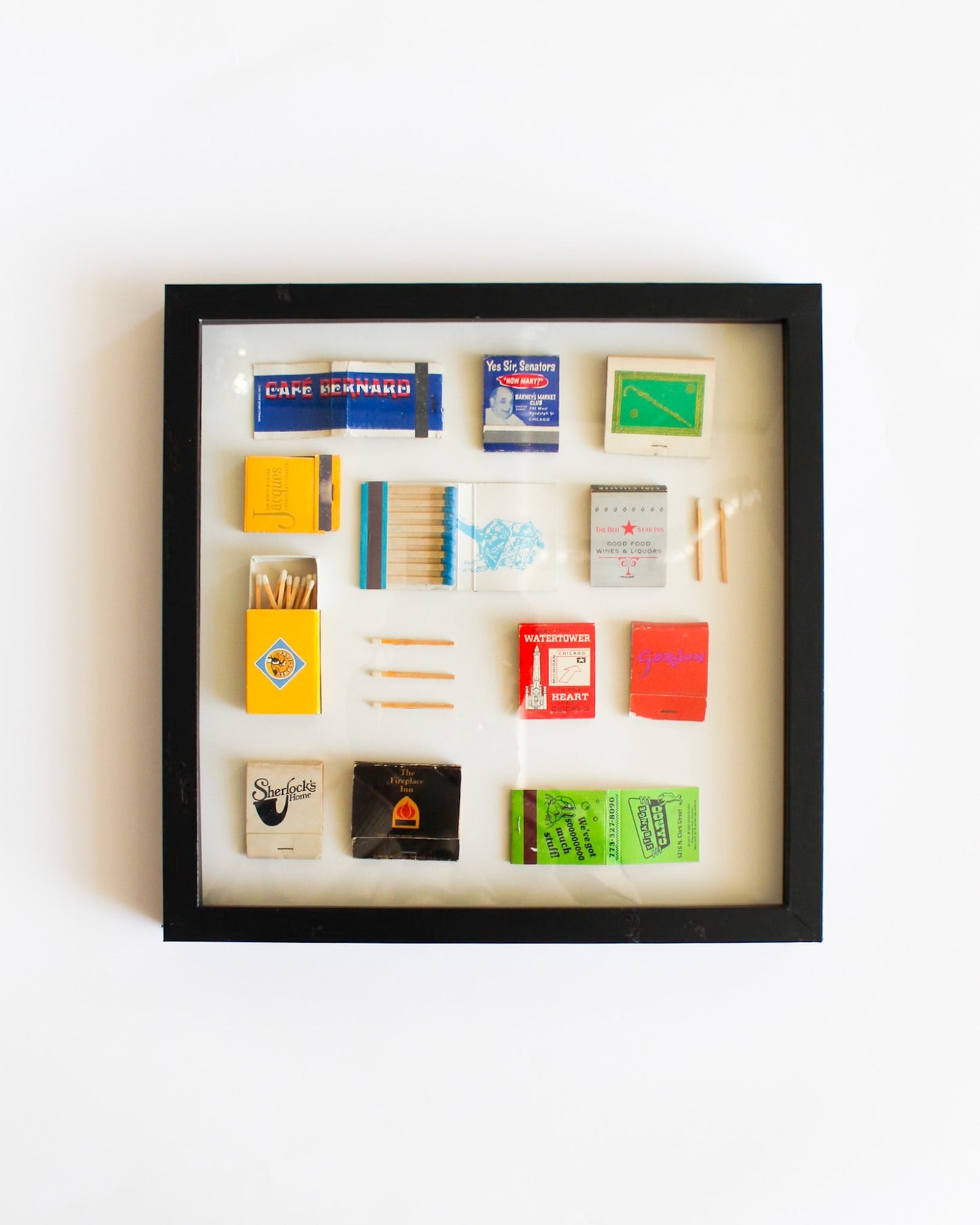 Framed display of matchbooks and matches on a white background