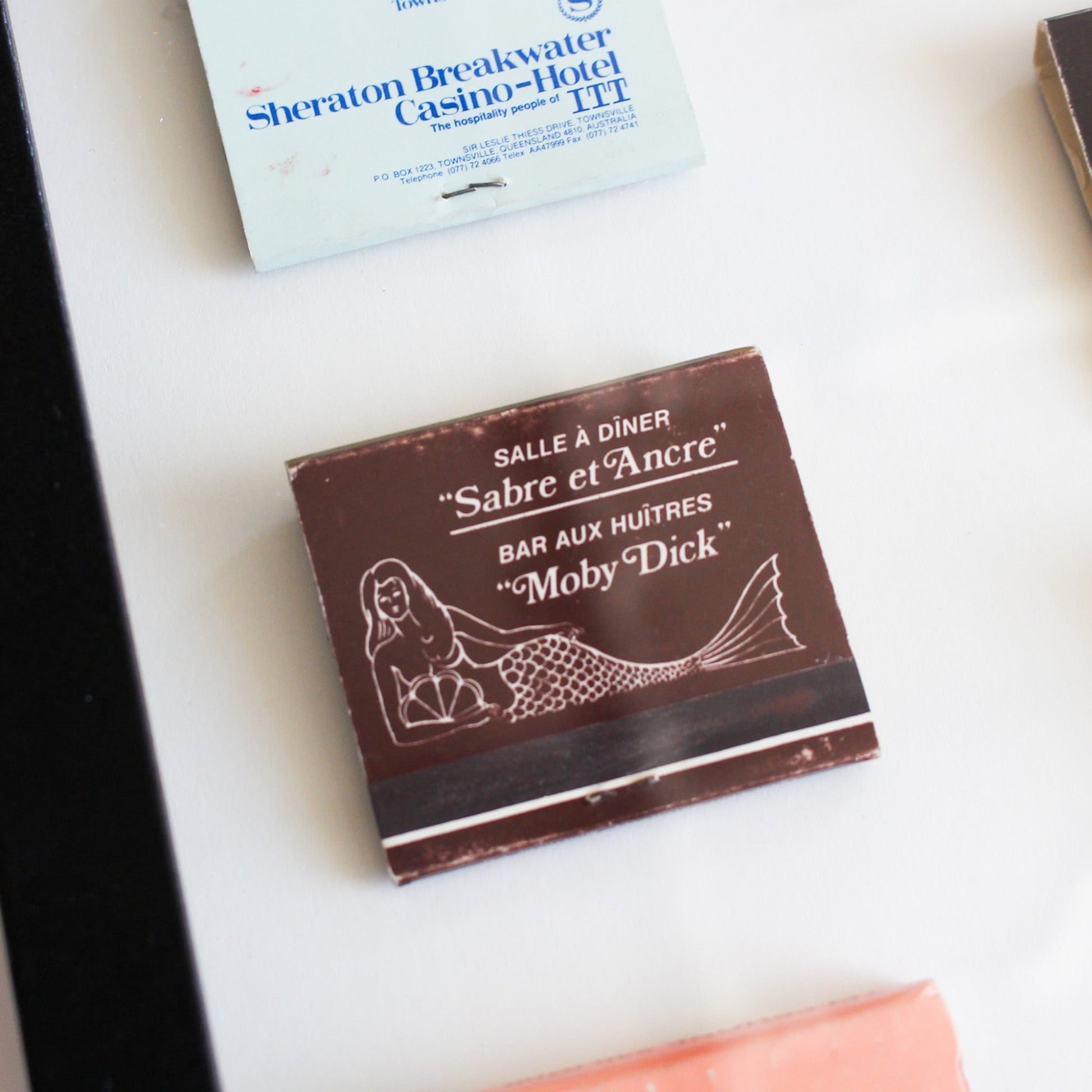 Matchbook with 'Sabre et Ancre' and 'Moby Dick' branding on a white surface