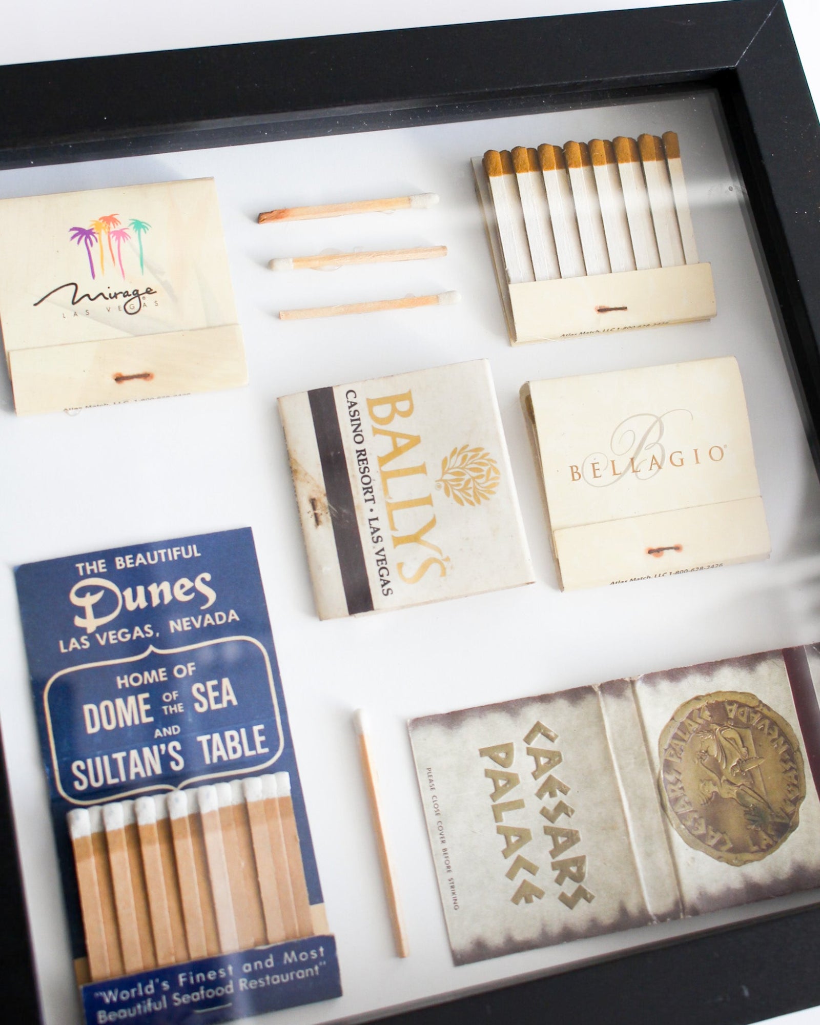 Collection of vintage matchbooks from famous hotels in Las Vegas displayed in a case.