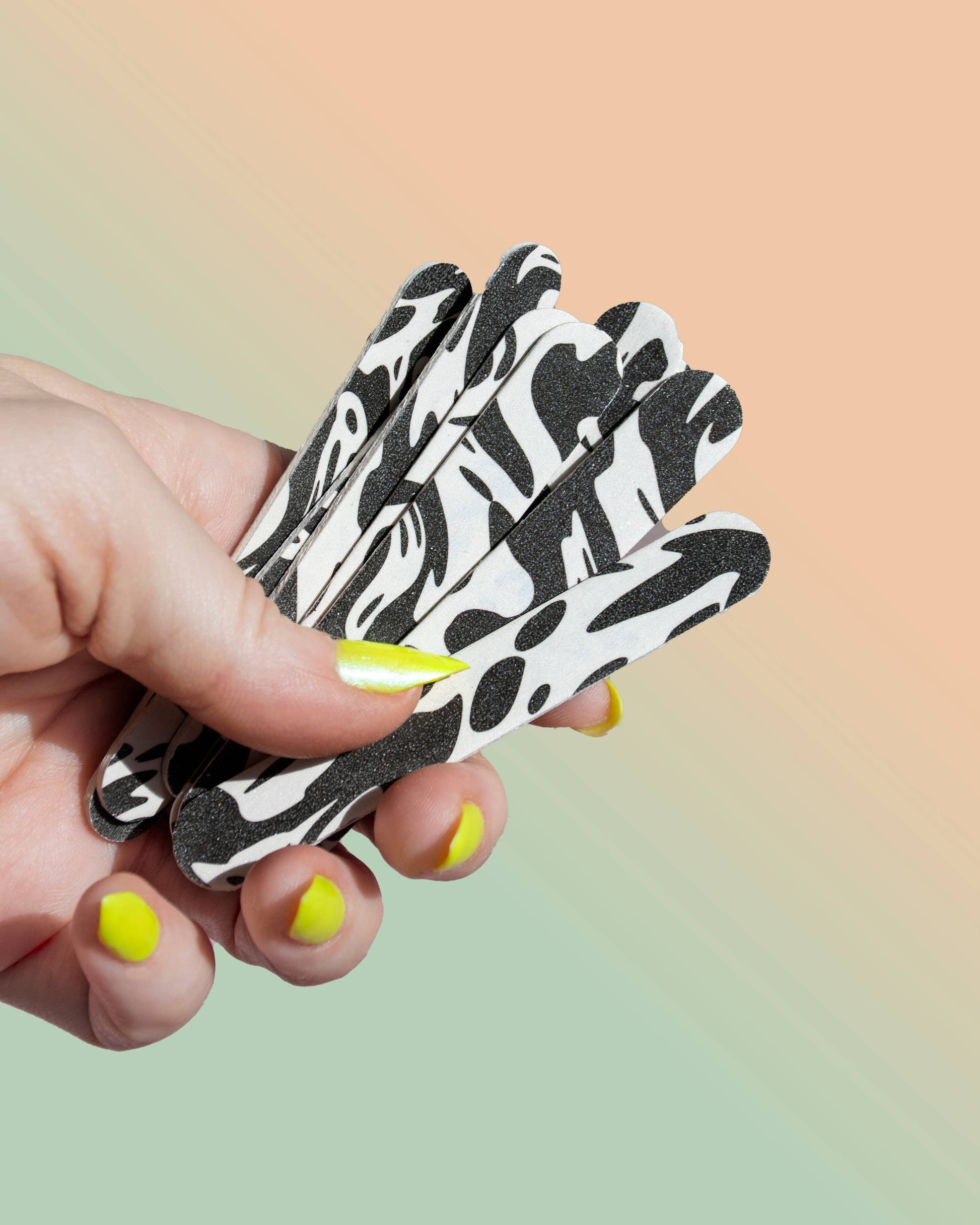 Hand holding black and white patterned gloves against a gradient background