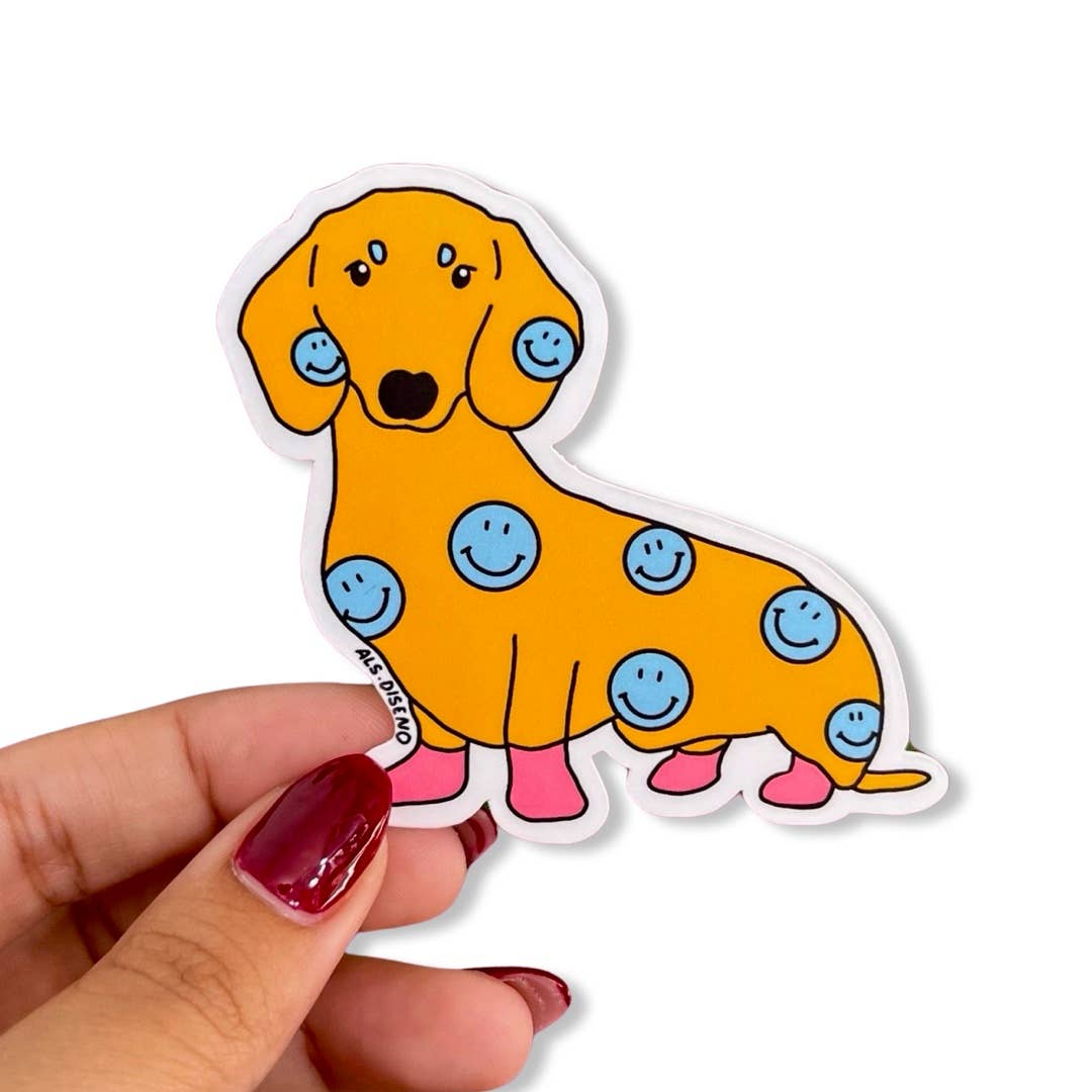 Sticker of a yellow dog with blue smiley face spots held by a hand on a white background