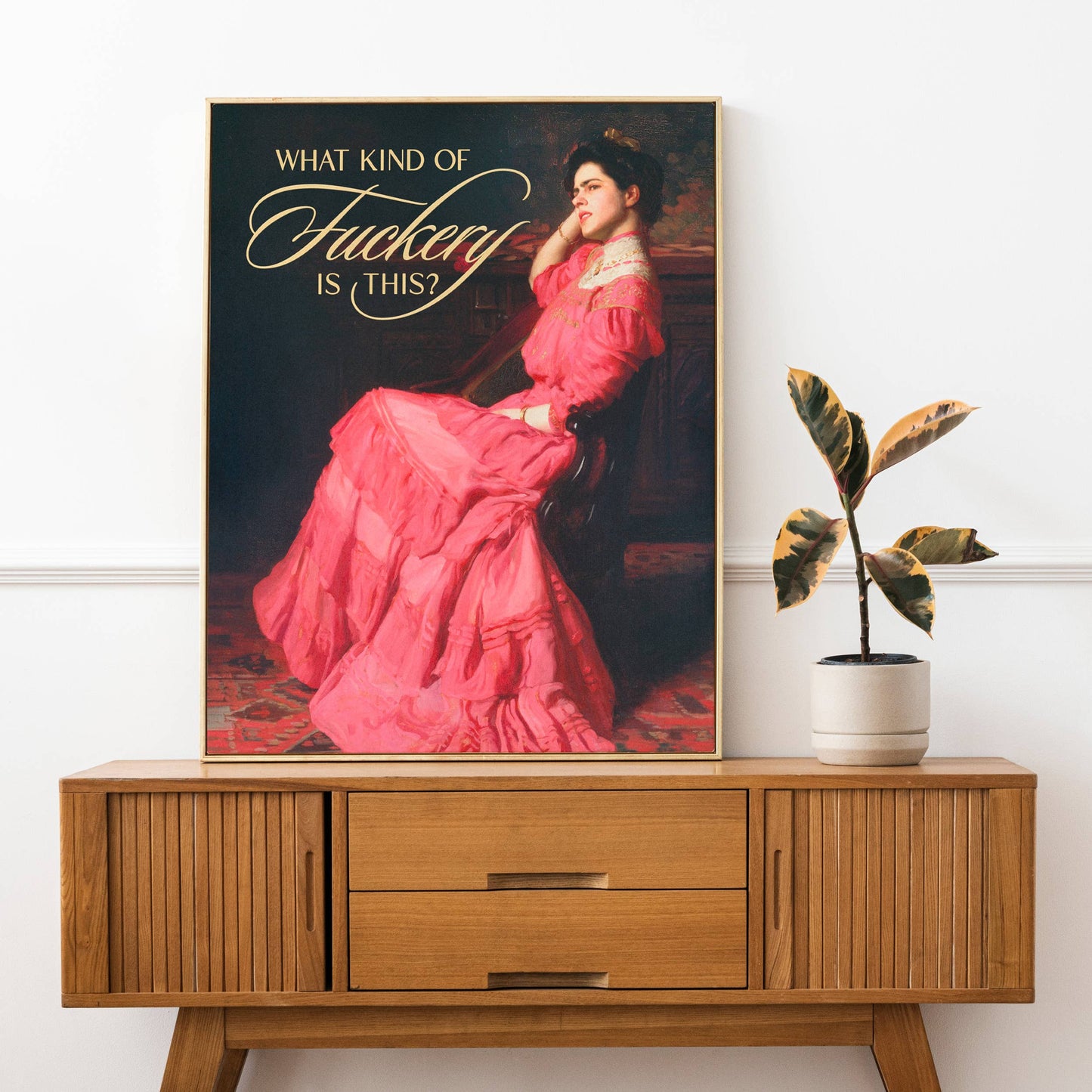 Poster of a woman in a pink dress with text on a wooden cabinet with a plant.