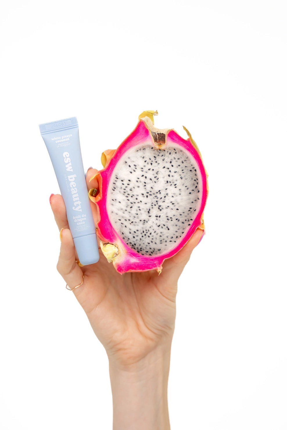 Hand holding a dragon fruit with a tube of 'Easy Beauty' product on a white background