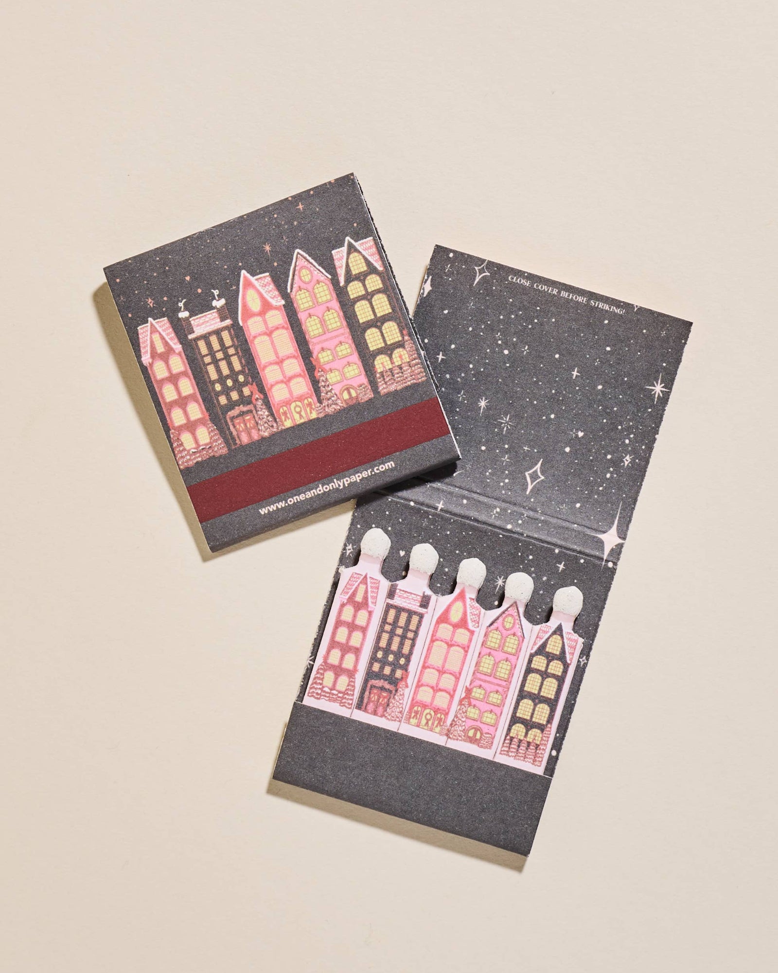 Two small matchbooks with illustrated houses design on a beige background. Wintry Village Printed Matchbook