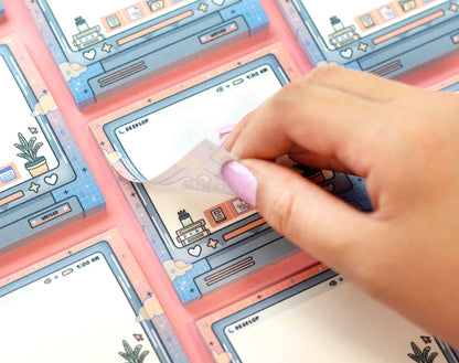 Hand holding a notepad with a colorful digital drawing tablet with cartoon-style interface